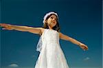 young girl with spreads arms against blue sky