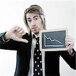 A portrait of a young businessman showing a blackboard with descending  stats and give his thumb down like he is pessimistic.