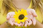 Young woman/girl gently holding a sunflower.