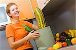 Yong woman with packet of vegetables in the kitchen after market