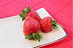 Three strawberries on a white plate