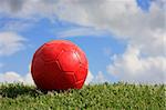 A red ball on a playing field with a cloudy sky