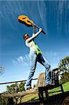 Woman over a long chair playing guitar and dancing