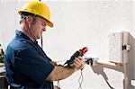 Electrician using a meter to check the voltage on an outdoor receptacle.  Model is a licensed master electrican and all work is performed according to  industry code and safety standards.