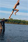 boy diving into the river from the wooden narrow pier