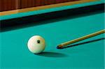 The white billiard-ball number 12 and wood cue on a green table