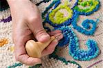 Hooking a mat, a traditional Newfoundland craft that recyles old fabrics into vibrant mats using burlap.