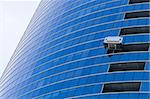 Two window cleaners in a gondola cleaning the windows of a corporate office skyscraper.