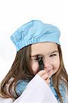 Toddler girl in blue medical scrubs looking through a medical instrument as if examining someone.