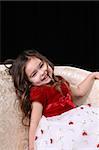 Pretty little girl in red and white dress on a couch.