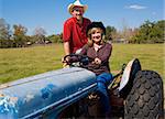 Beautiful mature couple riding a tractor on their farm.