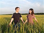 Young Couple Walking Field Holding Hands looking each other