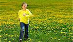 The girl runs on a green grass with dandelions