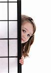 Pretty Little girl peeking out from behind a screen.