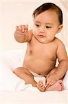 Asian infant sitting and pointing his finger out
