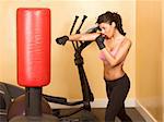 Attractive woman kickboxing using red punching bag
