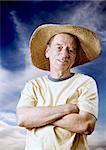 Senior man in a straw hat in front of cloudy sky