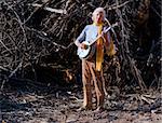 Barefoot banjo Player in Fraont of a Big Pile of Wood