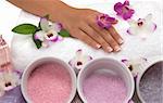 Pedicured hands, different kinds of cyrstal bath salts, lotions, massage oils, towel, mint and exotic orchids