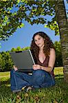 A beautiful young girl, using her laptop on a park.