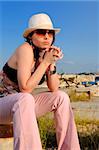 Young stylish woman posing outdoors with hat and sunglasses