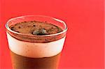 Glass of mousse a chocolat on a red background. Space left for text.