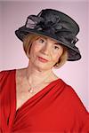 portrait of very attractive older woman wearing black hat and red dress