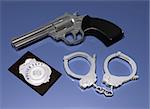 Illustration of a police gun, badge and pair of handcuffs on a blue background