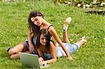 two nice student girl laying on the grass and studing with laptop