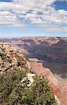 A shot of a partially cloud covered Grand Canyon from the South Rim, looking out on a trail to the Colorado.