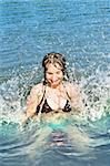 Young girl playing and splashing in a lake