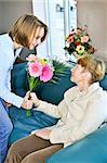 Granddaughter bringing colorful flowers to her grandmother