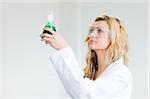 Woman in lapcoat looking at chemicals 2