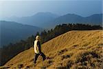 A man watch toward the mountain with golden grassland.