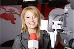 young beautiful television news reporter in front of the video camera smiling and looking at the camera in studio in live transmission