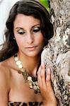 Portrait of a beautiful brunette woman standing by a tree.