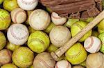 a picture of baseballs, softballs, a bat and glove