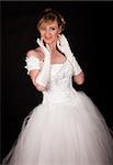 Attractive blond woman wearing white wedding gown with wide flowing skirt over black smiling