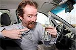 Man sitting in drivers with a bottle alcohol