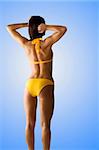 brunetta in yellow bikini showing her back side fitness body