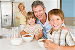 Father With Children As They Eat Breakfast And Mother In The Bac