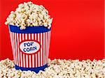 A popcorn bucket over a red background.