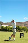 Young male golfer hitting the ball from the fairway on a beautiful summer day