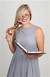 Portrait of a beautiful blonde woman with light blue eyes and classic make-up holding an organizer on grey background