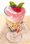 Healthy breakfast with muesli, raspberries, blueberries and yoghurt, decorated with mint leaves in a glass