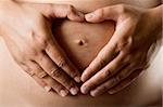 Pregnant women wrap her arms around the belly in the form of the heart. Isolated on white.