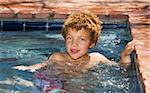 Cute young boy with green eyes in a swimming pool