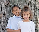 Two Cute Girls Smiling in Front of a Tree