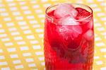 A glass of sparkling raspberry punch outdoors in a natural setting