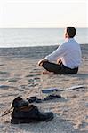 Businessman relaxing on beach - Focus on the shoes in the foreground